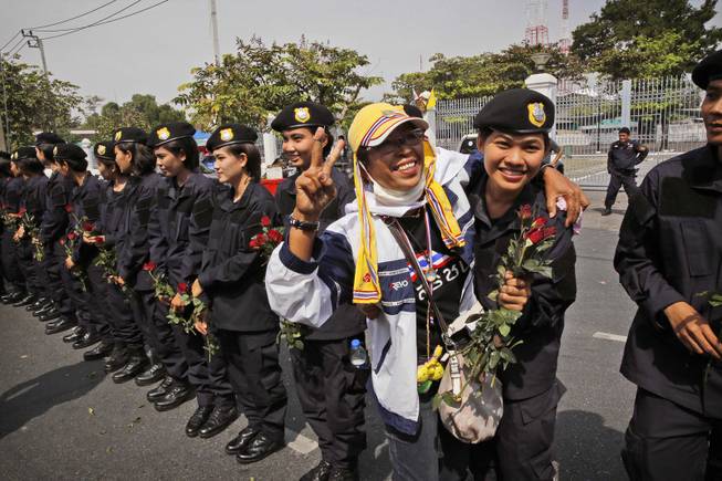 An anti-government protester hugs a Thai policewomen outside city police headquarters in Bangkok, Thailand, Tuesday, Dec. 3, 2013. 
