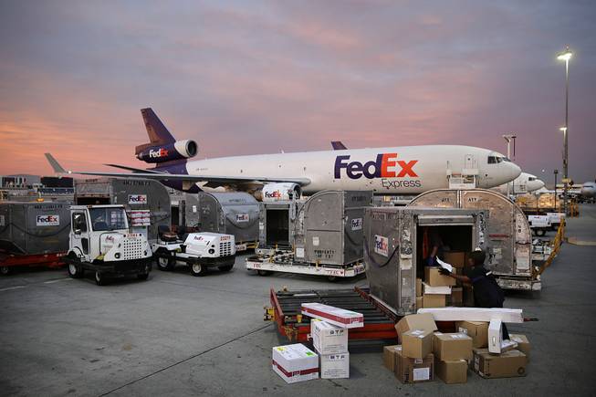 Brenda Thompson, right, loads packages into a container at the FedEx hub at Los Angeles International Airport on Monday, Dec. 2, 2013, in Los Angeles. 