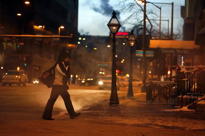 At dawn and in -9 degree weather, a woman braves the cold in downtown Denver, Thursday Dec. 5, 2013. A wintry storm pushing through the western half of the country has brought bitterly cold temperatures that prompted safety warnings for residents in the Rockies and threatened crops as far south as California.