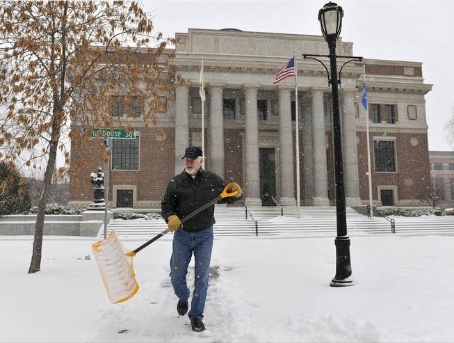 Bail Bondsman Tom Farrell clears the snow from the sidewalks outside his business adjacent to the Stearns County Courthouse Wednesday, Dec. 4, 2013, in downtown St. Cloud, Minn.