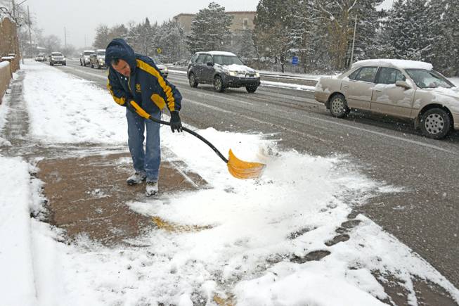 David Palomino clears the sidewalk of snow on Thursday, Dec. 5, 2013 in Santa Fe, N.M. Some northern New Mexico highways have difficult driving conditions Thursday as the latest blast of freezing temperatures, wind and snow causes delays and closures in parts of the state. National Weather Service forecasters say snowfall accumulations in some areas could reach 6 to 8 inches, with hardest-hit areas expected to include Torrance County and north toward Las Vegas.