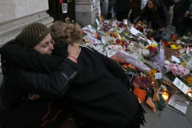 Two women embrace after they placed their floral tributes for Nelson Mandela outside the South Africa High Commission in London, Friday, Dec. 6, 2013.
