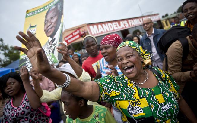 Mourners sing and dance to celebrate the life of Nelson Mandela, in the street outside his old house in Soweto, Johannesburg, South Africa, Friday, Dec. 6, 2013. 