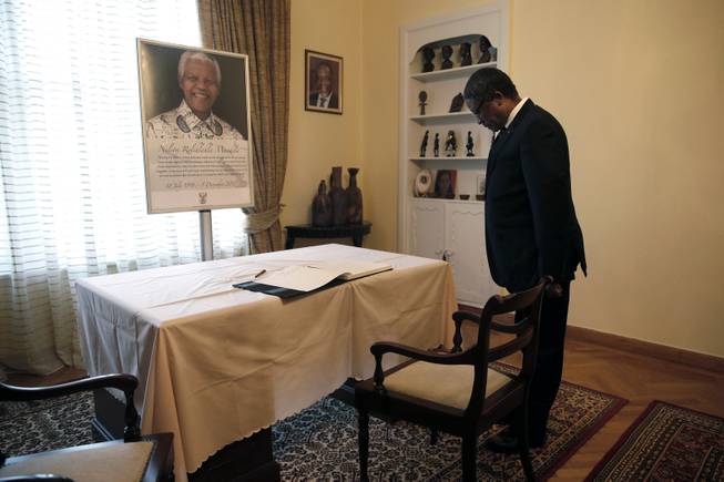 South Africa's ambassador to Greece S.R. Makgetla pauses in front of a picture of former President of South Africa, Nelson Mandela, in Athens, Friday, Dec. 6, 2013. 