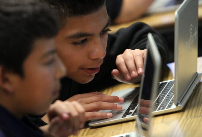 Pinacate Middle School students Raul Curil, 13, from left, and Marco Fuentes, 12, work on Chromebook devices producing their electronic newspaper the Puma Press in journalism class, Dec. 6, 2013, in Perris, Calif.
