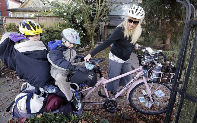 Madi Carlson maneuvers the family cargo bike as her sons Rijder, 4, left, and Brandt, 6, sit aboard in Seattle on Wednesday, Nov. 27, 2013. 