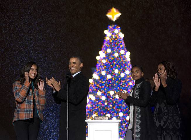 A rain falls, President Barack Obama, first lady Michelle Obama, and their daughters Sasha, second from right, and Malia, left, react as they light the National Christmas Tree during the National Christmas Tree Lighting ceremony at the Ellipse in Washington, Friday, Dec. 6, 2013. 