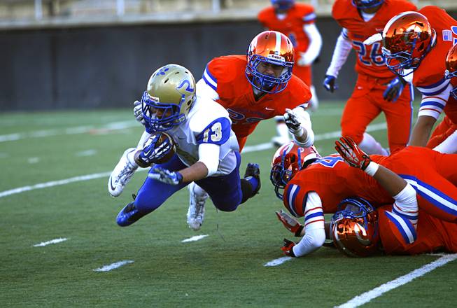Reed High School wide receiver Jorden Carter (13) is tripped up by members of the Bishop Gorman defense during their Division I state high school football championship game at Sam Boyd Stadium Saturday, Dec. 7, 2013.