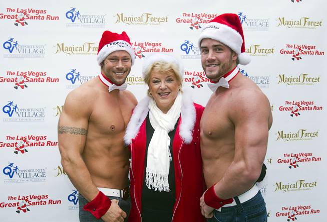 Las Vegas Mayor Carolyn Goodman is flanked by Chippendale dancers Jace Crispin and Gavin McHale during the annual Las Vegas Great Santa Run in downtown Las Vegas on Saturday, Dec. 7, 2013. 