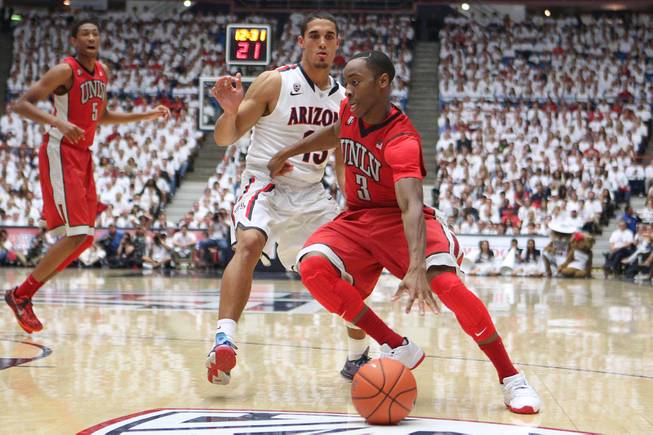 UNLV guard Kevin Olekaibe drives around Arizona guard Nick Johnson during their game at the McKale Center in Tucson Saturday, Dec. 7, 2013. Arizona won the game 63-58.