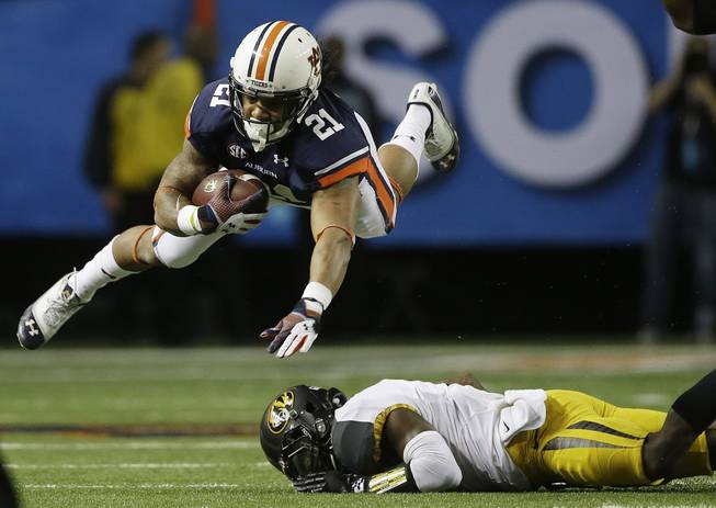 Auburn running back Tre Mason makes the catch and goes over Missouri defensive back John Gibson during the first half of the Southeastern Conference NCAA football championship game Saturday, Dec. 7, 2013, in Atlanta.