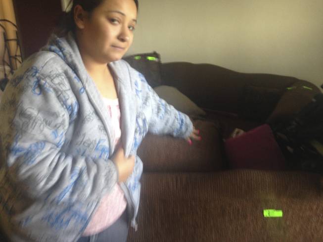 Valerie Sahagun examines the path of a bullet that whizzed through her home early Saturday, Dec. 7, 2013.