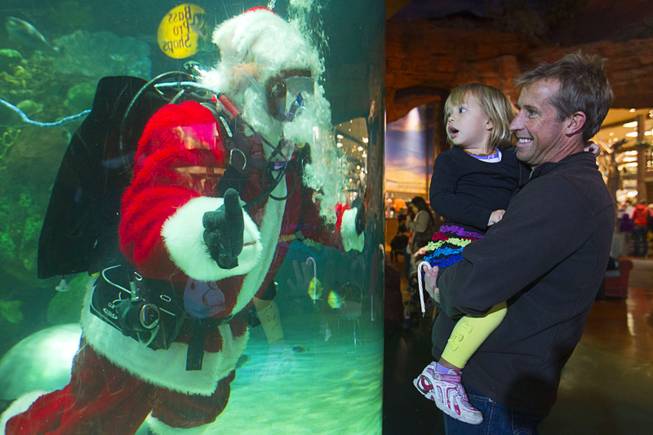 Jesse Sodergren, 2, of San Clemente, Calif,.  is held by her father james as she checks out an underwater Santa Claus at the Silverton Casino Hotel in Las Vegas, Nevada December 8, 2013. The underwater Santa and his helpers greet visitors and take present requests from inside the casino's 117,000-gallon aquarium on weekends in December until Christmas.