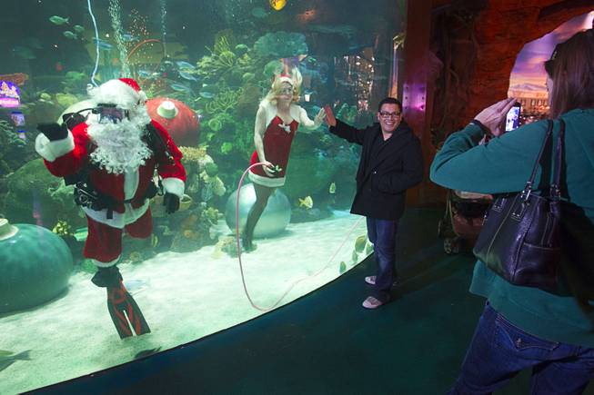 Oscar Rivera of Los Angeles has his photo taken with underwater Santa Claus and Nicole, one of Santa's helpers, at the Silverton Casino Hotel in Las Vegas, Nevada December 8, 2013. The underwater Santa and his helpers greet visitors and take present requests from inside the casino's 117,000-gallon aquarium on weekends in December until Christmas.