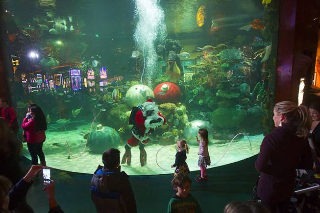 An underwater Santa Claus interacts with children at the Silverton Casino Hotel in Las Vegas, Nevada December 8, 2013. The underwater Santa and his helpers greet visitors and take present requests from inside the casino's 117,000-gallon aquarium on weekends in December until Christmas. Santa is equipped with a microphone that allows him to listen to and speak with the children.