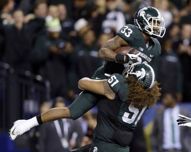 Michigan State's Jeremy Langford (33) celebrates with Fou Fonoti (51) after Langford ran 26 yards for a touchdown during the fourth quarter of the Big Ten Conference championship against Ohio State, Saturday, Dec. 7, 2013, in Indianapolis. 