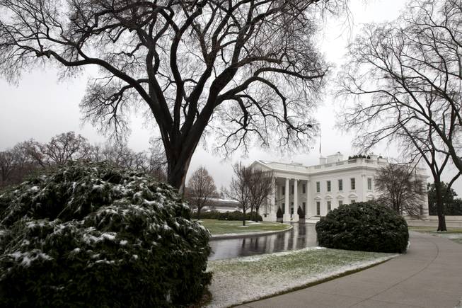 The White House is reflected in the driveway by melting snow and ice in Washington, Monday, Dec. 9, 2013. Rain is expected in the Washington region Monday, with snow possible in the evening, according to the National Weather Service.