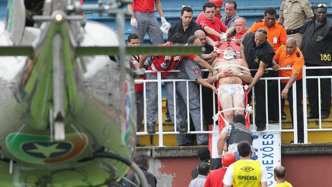 An injured fan is carried on a stretcher after clashes with team fans during a Brazilian league soccer match between Atletico Paranaense and Vasco da Gama in Joinville, southern Brazil, Sunday, Dec. 8, 2013. 