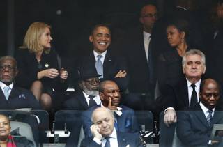 President Barack Obama jokes with Danish prime minister, Helle Thorning-Schmidt, left, as first lady Michelle Obama looks on at right during the memorial service for former South African president Nelson Mandela at the FNB Stadium in Soweto, near Johannesburg, South Africa, Tuesday Dec. 10, 2013.