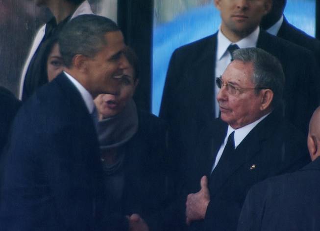 In this image from TV, US President Barack Obama shakes hands with Cuban President Raul Castro at the FNB Stadium in Soweto, South Africa, in the rain for a memorial service for former South African President Nelson Mandela, Tuesday Dec. 10, 2013. The handshake between the leaders of the two Cold War enemies came during a ceremony that's focused on Mandela's legacy of reconciliation.