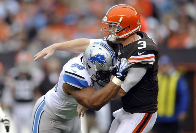 Cleveland Browns quarterback Brandon Weeden is hit by Detroit Lions defensive tackle Ndamukong Suh after throwing a pass in the first quarter of an NFL football game in Cleveland, Oct. 13, 2013. Suh, who wasn't penalized on the play, was fined by the league for the hit. 