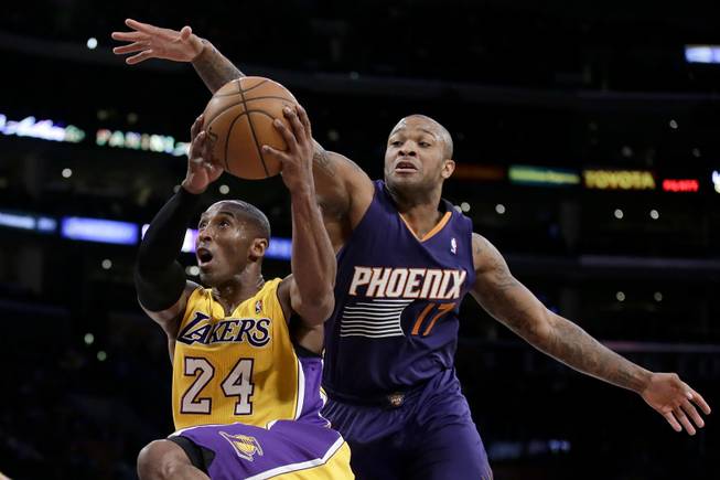 Los Angeles Lakers guard Kobe Bryant, left, drives to the basket past Phoenix Suns forward P.J. Tucker during the first half of an NBA basketball game in Los Angeles, Tuesday, Dec. 10, 2013.