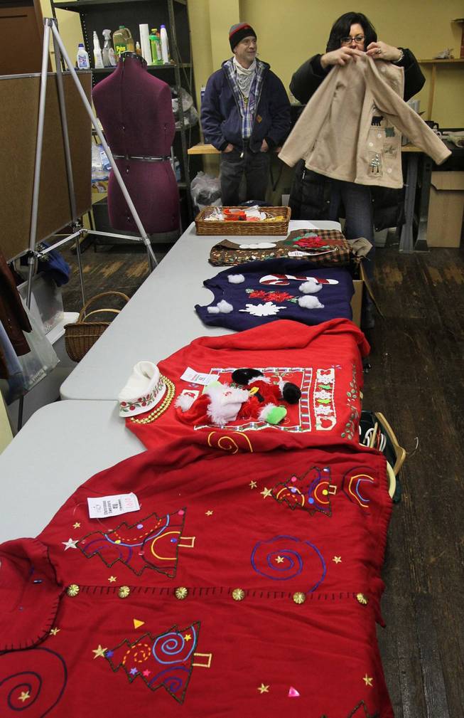 Vicki Vespoint, of Cuyahoga Falls, right, and her husband, Jim, search through the stash of ugly Christmas sweaters and vests owned by Troy Zulich at his warehouse, Dec. 11, 2013, in Akron, Ohio.