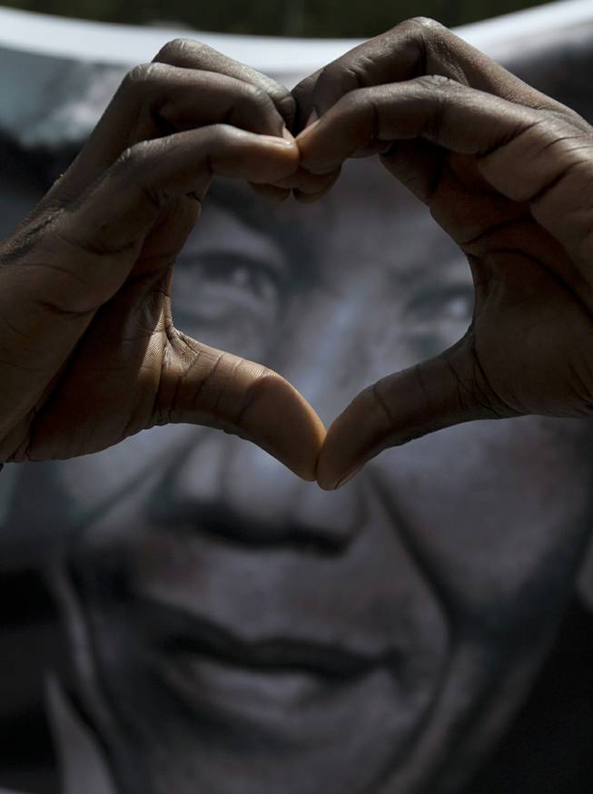 A man forms a heart when taking part in a march for former President Nelson Mandela outside the Union Buildings in Pretoria Wednesday Dec. 11, 2013, where the body of Mandela lies in state for three days. 
