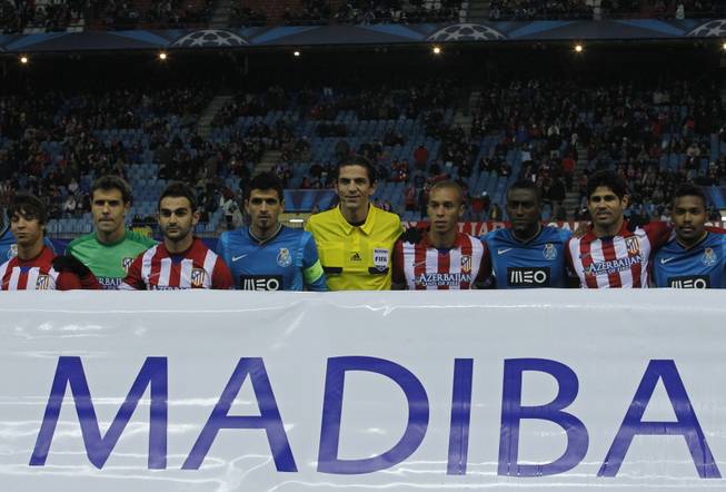 The referee, center, stands with Atletico and Porto players as they pose with a banner in support of former South African president Nelson Mandela, before the kick-off during a Group G Champions League soccer match between Atletico Madrid and FC Porto at the Vicente Calderon stadium in Madrid, Wednesday Dec. 11, 2013. 