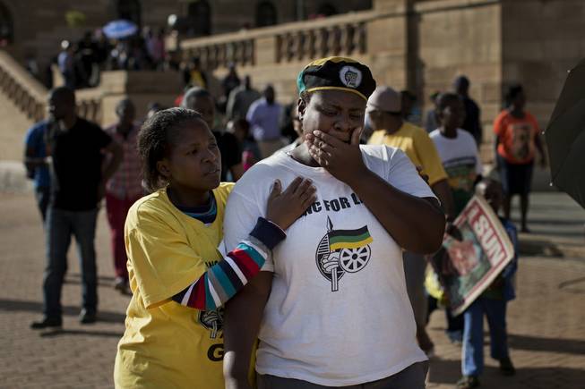 A mourner shows emotion after visiting the Union Buildings where the casket of Former President Mandela lies in state for three days, in Pretoria, South Africa, Wednesday, Dec. 11, 2013.