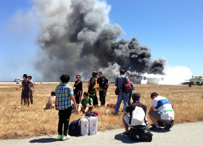  This Saturday, July 6, 2013, file photo provided by passenger Benjamin Levy, shows fellow passengers from Asiana Airlines flight 214, many with their luggage, on the tarmac just moments after the plane crashed at the San Francisco International Airport in San Francisco.