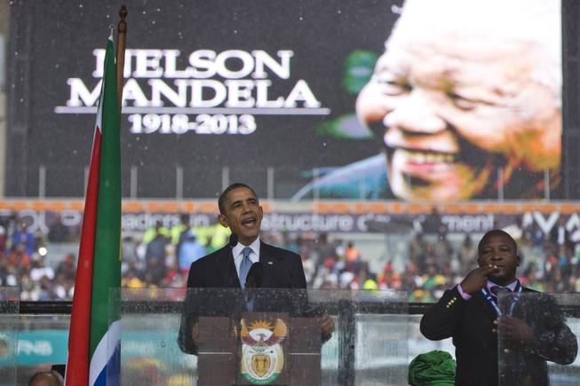 President Barack Obama delivers his speech next to a sign language interpreter during a memorial service at FNB Stadium in honor of Nelson Mandela on Tuesday, Dec. 10, 2013 in Soweto, near Johannesburg. The national director of the Deaf Federation of South Africa says a man who provided sign language interpretation on stage for Nelson Mandela’s memorial service in a soccer stadium was a “fake."