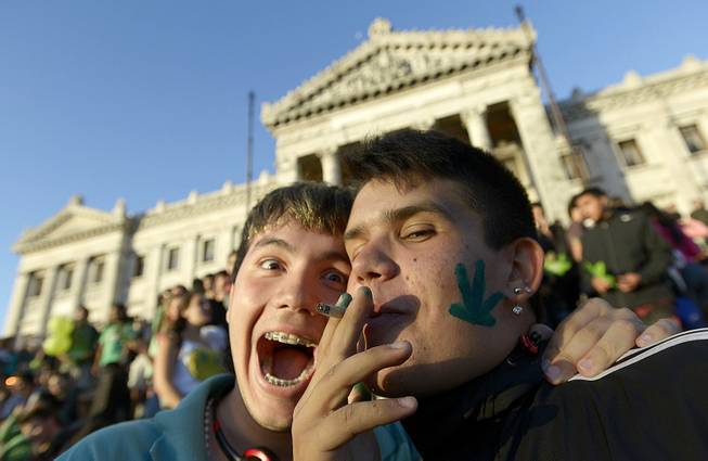 An activist smokes a marijuana cigarette as he poses for photos in front of the Congress in Montevideo, Uruguay, Tuesday, Dec. 10, 2013. 