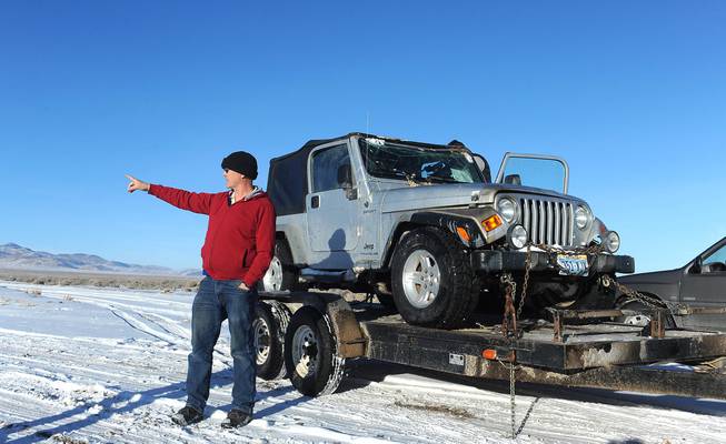 Charles Sparke, Pershing County director of emergency management points in the direction of the mountain range where a family spent two nights in 15 degree weather after their Jeep, being towed in this photograph, rolled over during an outing in the Seven Troughs Range in Lovelock, Nev. The couple and four children where found alive on Tuesday.
