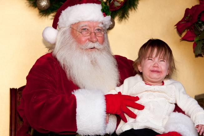 Fifteen-month-old Taylor Ireland bawls in the arms of Santa Claus while visiting him in his cottage at Tivoli Village in Las Vegas Friday, December 13, 2013.  Larry Hansen has been donning the coveted suit and sharing the spirit of Santa for over nine years in Las Vegas.
