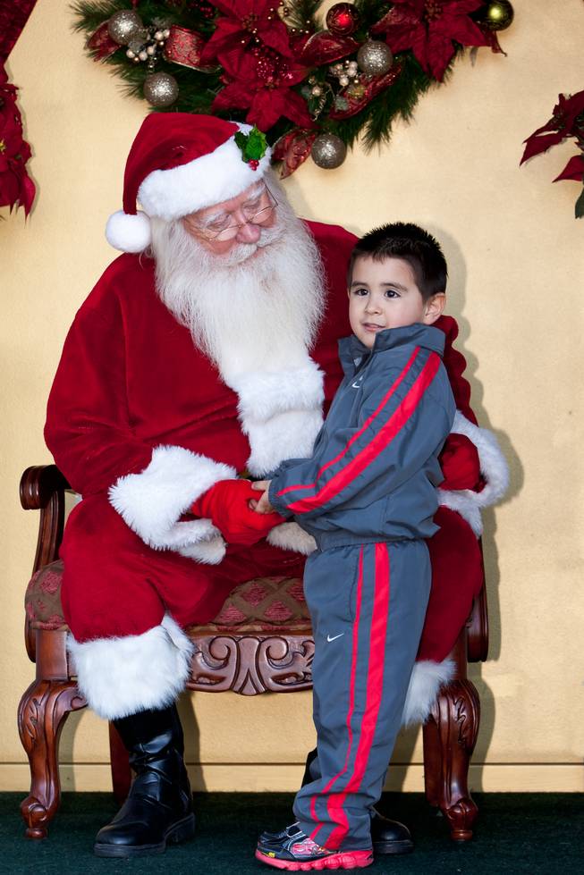 Santa Claus asks Matthew Trujillo, 3, what he wants for Christmas while visiting him in his cottage at Tivoli Village in Las Vegas Friday, December 13, 2013.  Larry Hansen has been donning the coveted suit and sharing the spirit of Santa for over nine years in Las Vegas.