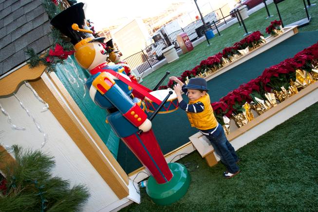Three-year-old Jack Fritz entertains himself playing on a toy soldier's drum while waiting for Santa to arrive at his cottage in Tivoli Village in Las Vegas Friday, December 13, 2013.