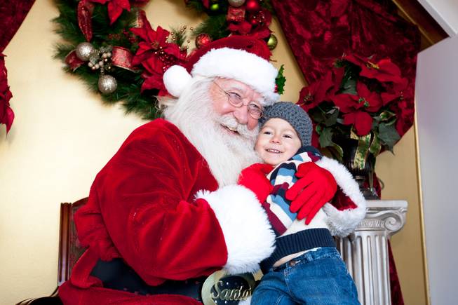 Callan McClish, 2, grins ear to ear as he receives the first hug of the day by Santa Claus in his cottage at Tivoli Village in Las Vegas Friday, December 13, 2013. Larry Hansen has been donning the coveted suit and sharing the spirit of Santa for over nine years in Las Vegas.