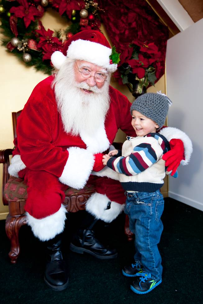 Santa Claus smiles after learning two-year-old Callan McClish, right, tells him he wants a kitchen like his daddy's while visiting him in his cottage at Tivoli Village in Las Vegas Friday, December 13, 2013. Larry Hansen has been donning the coveted suit and sharing the spirit of Santa for over nine years in Las Vegas.