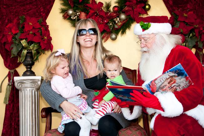 Kerri Johnson cracks up laughing as her daughters, two-year-old Sophie and eight-month-old Harlowe, burst into tears as Santa Claus reads to them while visiting him in his cottage at Tivoli Village in Las Vegas Friday, December 13, 2013.  Larry Hansen has been donning the coveted suit and sharing the spirit of Santa for over nine years in Las Vegas.