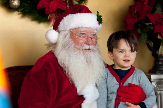 Two-year-old Bronson Frederick, who wants cars and trucks for Christmas, smiles for a photo with Santa Clause while visiting Santa in his cottage at Tivoli Village in Las Vegas Friday, December 13, 2013.  Larry Hansen has been donning the coveted suit and sharing the spirit of Santa for over nine years in Las Vegas.