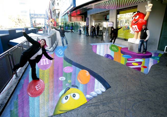 M&M'S World Las Vegas celebrates the recent opening of its new candy wall - the largest M&M'S candy wall in the world - with a 3-D chalk art installation by We Talk Chalk on the sidewalk outside the store on December 13, 2013 in Las Vegas, Nevada. Customers and pedestrians were encouraged to pose "in" the other-worldly image which featured the candy wall tubes and the floating M&M'S.