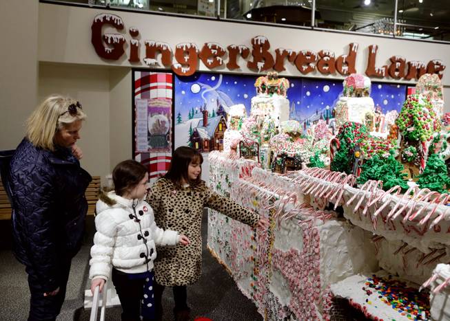 Lisa Grillo, left, accompanies Emily, 8, and Kate, 9, as they look at the GingerBread Lane, created by Chef Jon Lovitch, in the New York Hall of Science, in the Queens borough of New York,  Thursday, Dec. 12, 2013.