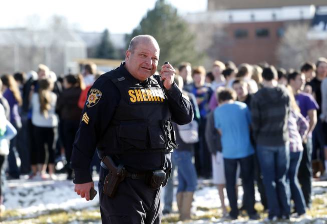 A sheriff deputy talks on his radio at Arapahoe High School in Centennial, Colo., on Friday, Dec. 13, 2013, where a student shot at least one other student at a Colorado high school Friday before he apparently killed himself, authorities said. 