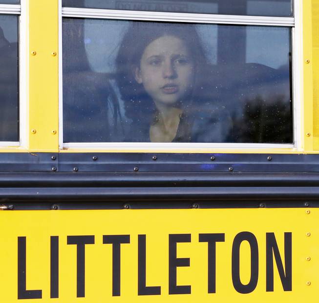 A student stares out a bus window as it arrives at a church to be reunited with family after students from nearby Arapahoe High School were evacuated their after a shooting at the school in Centennial, Colo., Friday, Dec. 13, 2013. 