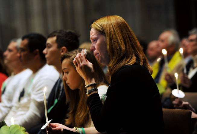 Miranda Pacchiana, center, of Newtown, Conn., wipes her eye during a National Vigil for Victims of Gun Violence just prior to the first anniversary marking the Sandy Hook Elementary School mass shooting at Washington National Cathedral on Thursday, Dec. 12, 2013, in Washington. Members of the Newtown, Conn., community, including the parent of a teacher killed in a school massacre a year ago, gathered for the vigil to remember those who lost their lives because of gun violence.