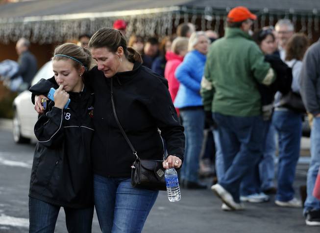 A parent picks up her daughter at a church where students from nearby Arapahoe High School were evacuated to after a shooting on the Centennial, Colo., campus Friday, Dec. 13, 2013. Arapahoe County Sheriff Grayson Robinson said the shooter shot two others at the school before apparently killing himself.