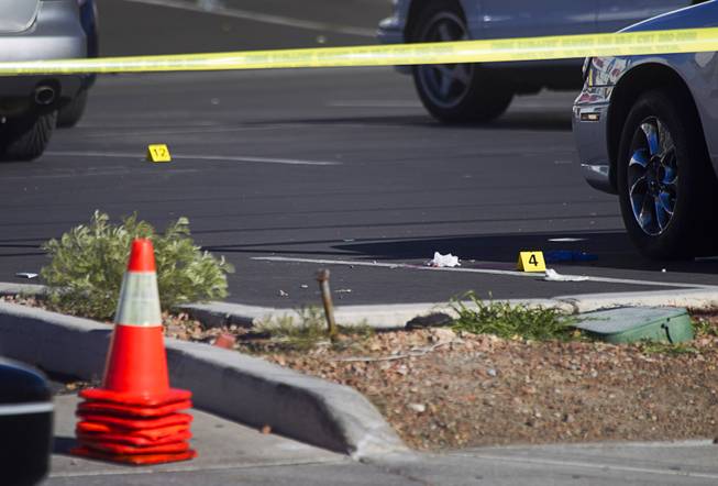 Evidence markers are shown in a parking lot as Metro police investigate a fatal shooting in front of a furniture store on Spring Mountain Road Sunday, Dec. 15, 2013.