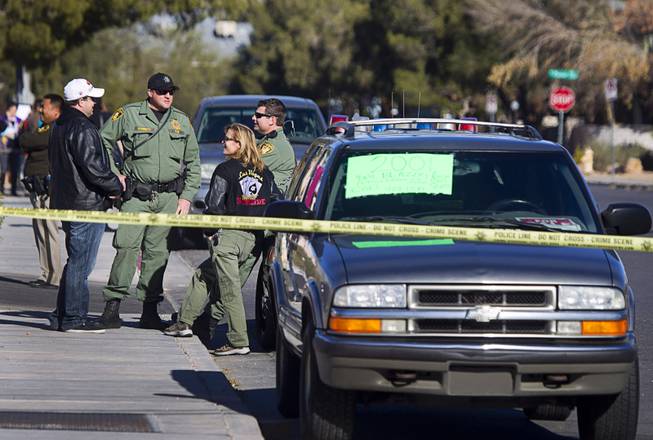 Metro Police officers stand by as detectives and crime scene analysts investigate a fatal shooting in front of a furniture store on Spring Mountain Road Sunday, Dec. 15, 2013.