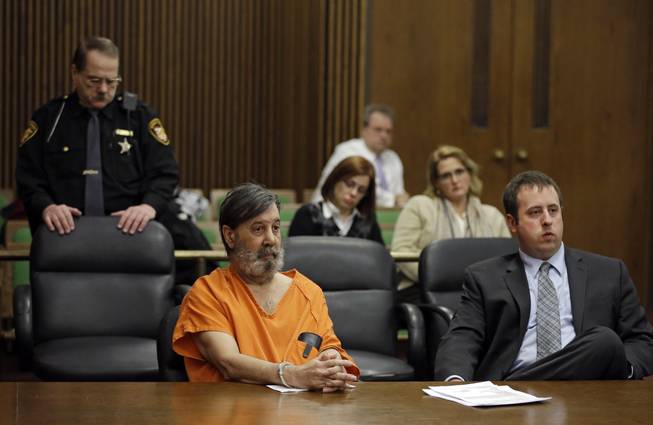 John Donald Cody, center, sits with attorney Joseph Patituce, right, during his sentencing on racketeering, theft, money laundering charges Monday, Dec. 16, 2013, in Cleveland. Cody, using the stolen identity Bobby Thompson, was sentenced to 28 years in prison for defrauding donors of up to $100 million in 41 states through the United States Navy Veterans Association, a charity he ran in Tampa, Fla.